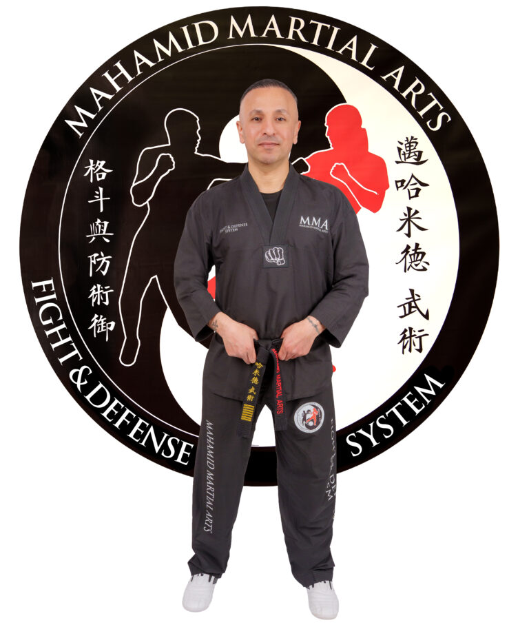 Sifu Hassan Mahamid im Kampfanzug vor dem Logo von Mahamid Martial Arts