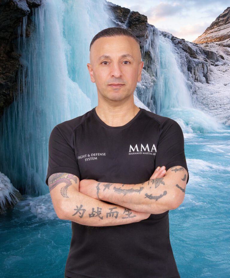 Sifu Hassan Mahamid mit verschränkten Armen vor einem Wasserfall
